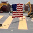 Two excavators holding giant knitted flag