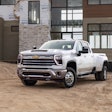 2024 Chevy Silverado 3500 parked in dirt area in front of building under construction