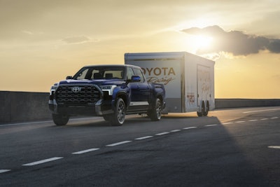 blue 2024 Toyota Tundra towing Toyota Racing trailer on highway