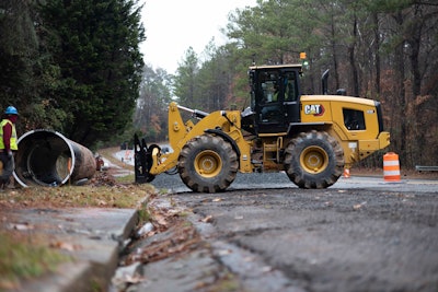 Cat 938 wheel loader approaching pipe with forks