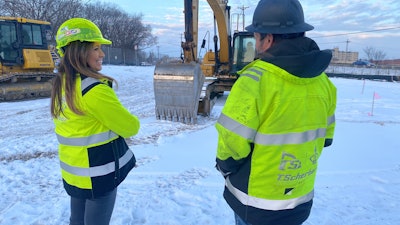 missy scherber and worker on snow-cover jobsite in front of Cat excavator and dozer