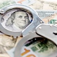 Handcuffs laying on top of 100 dollar bills