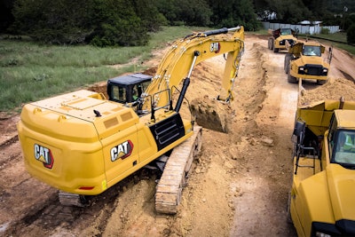 Cat 352 excavator digging trench beside dump truck