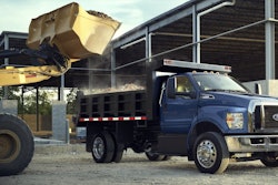 blue Ford F-750 truck wheel loader dumping load into bed