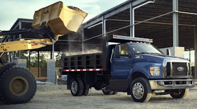blue Ford F-750 truck wheel loader dumping load into bed