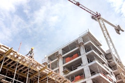 crane over under construction building with worker on top