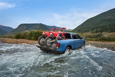 light blue 2024 Honda Ridgeline TrailSport crossing creek red motorcycles in bed