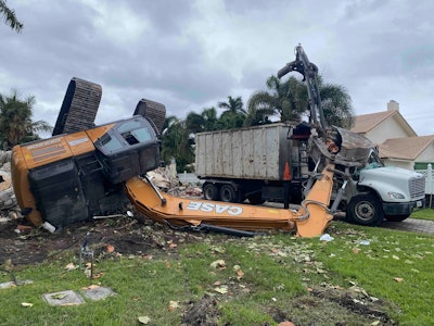 Case excavator overturned by debris pile bucket on top of crushed truck cab