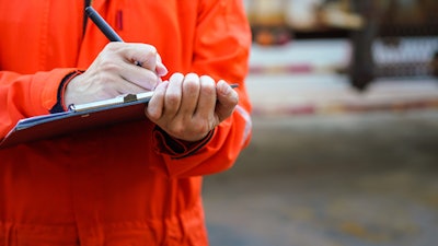 man orange coat writing in notebook