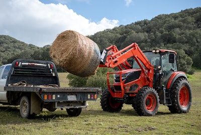 kioti hx series tractor loading a bale of hay
