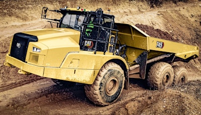 Cat 745 articulated dump truck climbing dirt road loaded with dirt