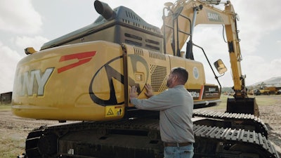 Man closing side panel on a Sany excavator from Newman Tractor
