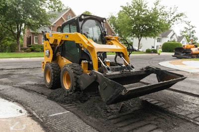 Cat 262D3 skid steer dumping asphalt on road