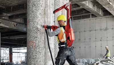 worker wearing Hilti EXO-T-22 tool balancer backpack drills into concrete column