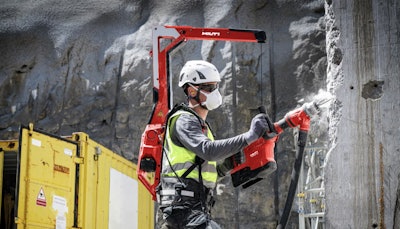 worker wearing Hilti EXO-T-22 tool balancer backpack drills into concrete column