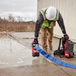 worker with Milwaukee Tool battery-powered submersible pump and backpack console by puddle