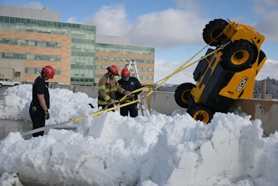 Madison Fire Department crews secure telehandler hanging off edge of parking garage with heavy duty straps