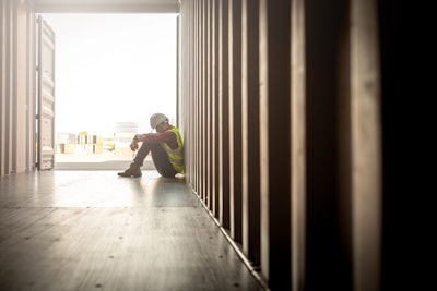 Construction worker sitting on the ground in despair
