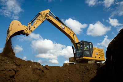 Cat 320 excavator dumping dirt beside hole