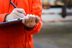 stock photo inspector in orage coat writing notes on clipboard