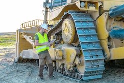 Construction worker using a tablet next to a large bulldozer