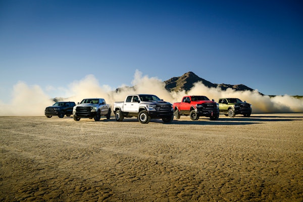5 offroad model ram pickups stirring up dust in desert