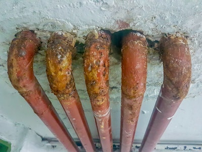 5 rusty red lead pipes in wall