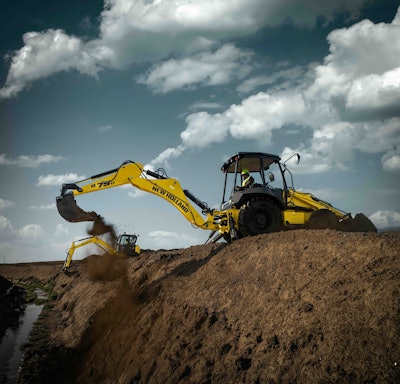 New Holland B75D backhoe on hilltop excavator front arm stretching out dumping bucket of dirt
