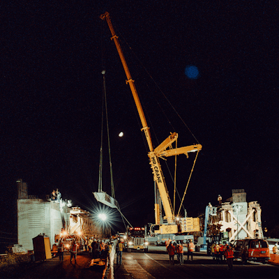 crane at night places first girder for Wallis Annenberg Wildlife Crossing over U.S. 101 in LA County