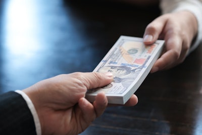 Man handing a stack of cash to another man