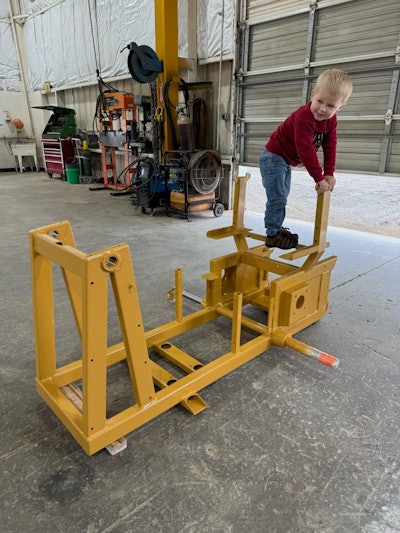 3 year old boy on mini dozer frame in shop