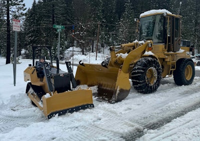 mini replica Cat D5 dozer with boy in seat beside large Cat wheel loader
