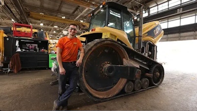 apprentice leans on Caterpillar machine