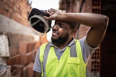 stock image worker wiping brow hard hat in hand