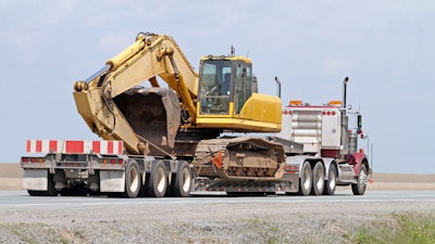 Excavator hauled by a semi truck and trailer