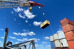 crane lifts shipping container off ship