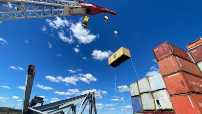 crane lifts shipping container off ship