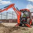 man uses rear mounted tractor backhoe on jobsite
