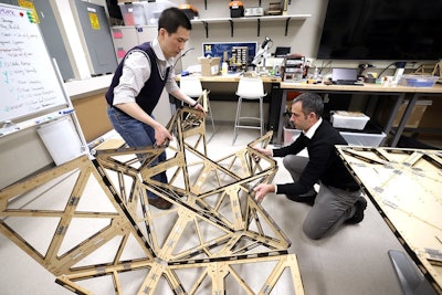 two professors unfold an origami structure