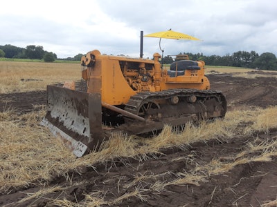 1950s Cat D7 dozer in field with Caterpillar umbrella