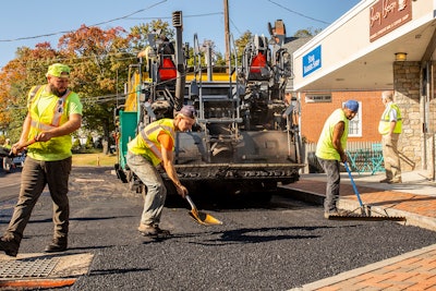 Nick D'Amico shoveling asphalt behind paver