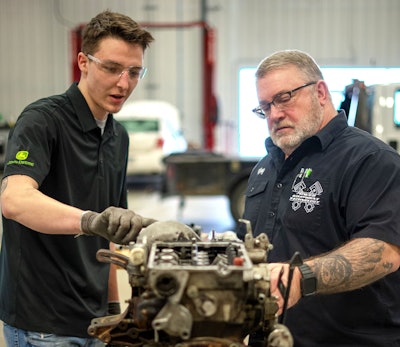 instructor and student work on small engine together