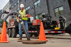 worker holding hose on Ditch Witch HX40G hydro-excavator over manhole