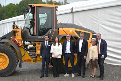 executives and Prince Philip stand in from of a Volvo wheel loader