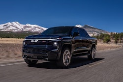 2025 dark blue 2025 Chevy Silverado EV on valley road wi snow-capped mountains background