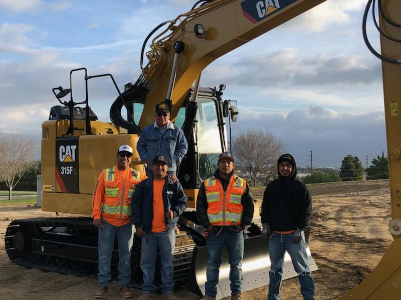 Buenas Brothers Construction owners next to a Cat excavator