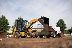 Cat 903 compact wheel loader dumping mulch onto trailer