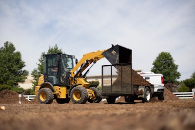 Cat 903 compact wheel loader dumping mulch onto trailer