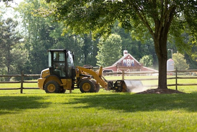 Cat 903 compact wheel loader cutting grass red barn in background