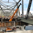 crane repairs a bridge over a river